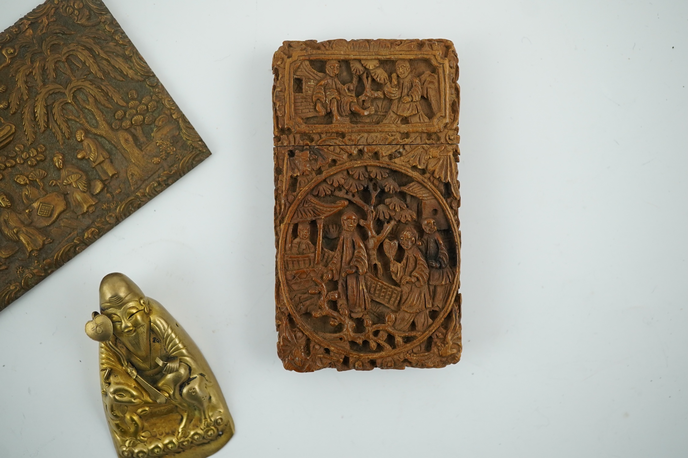 A Chinese carved sandalwood card case, a bronze relief cast and chased plaque and a gilt metal Shou Lao pendant, card case 7.5cm high. Condition - good